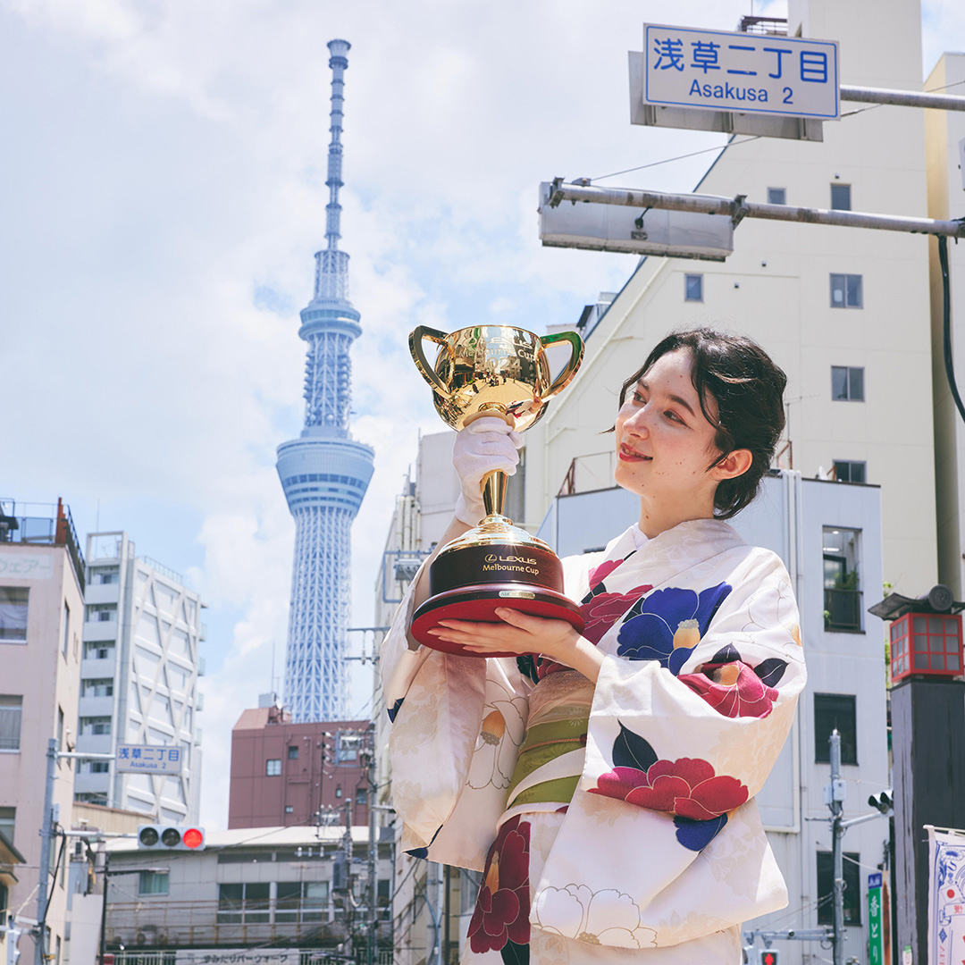 Woman holding Lexus Melbourne Cup in front of Tokyo Tower