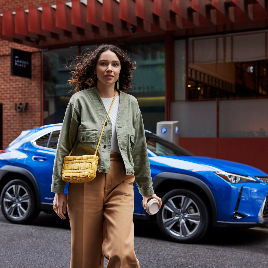 A woman walks away from a parked UX 300e