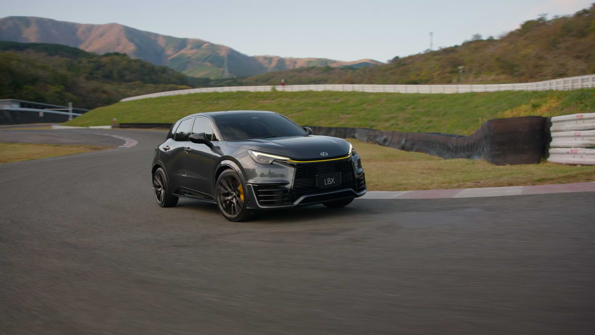 Black Lexus LBX Morizo RR concept model drives on a track with hills in the background